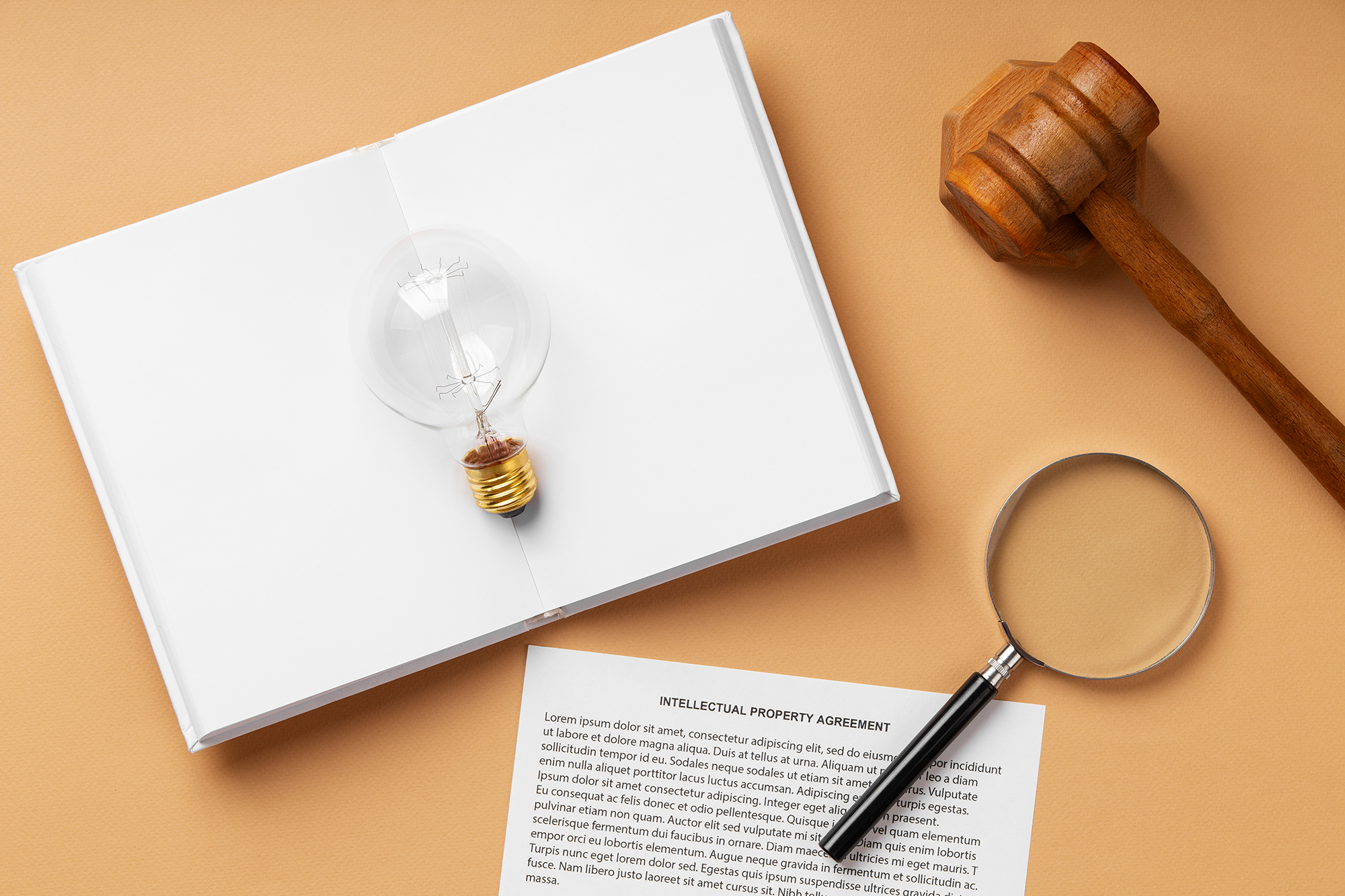 Items on a flat surface such as lightbulb on an open book, magnifying glass, and gavel